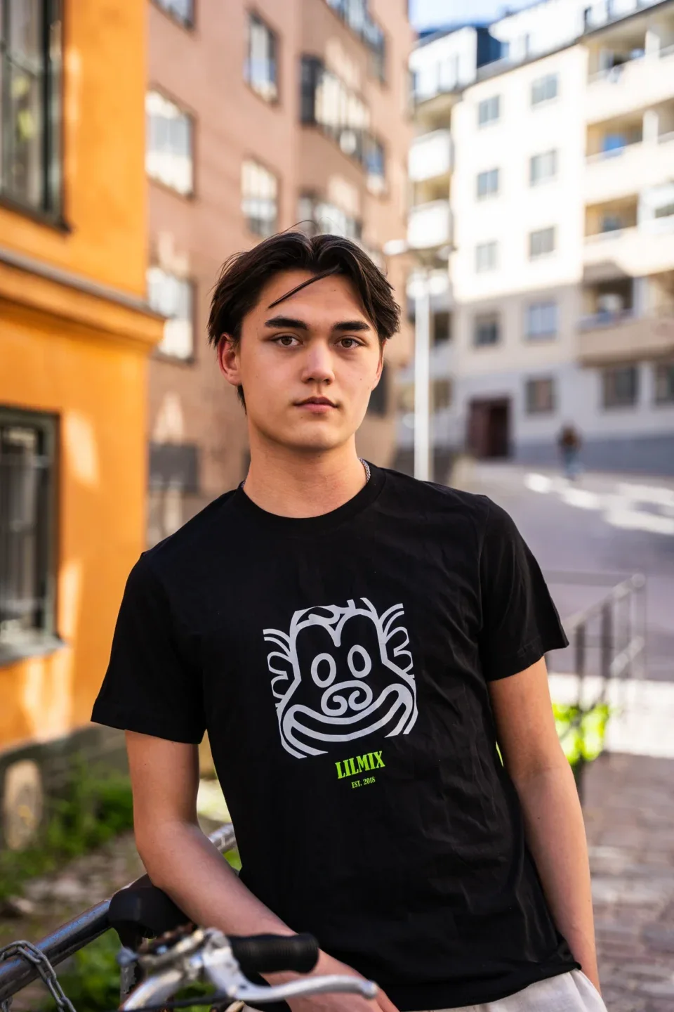 Black Lilmix Classic T-shirt with the monkey print, worn leaning on a bike